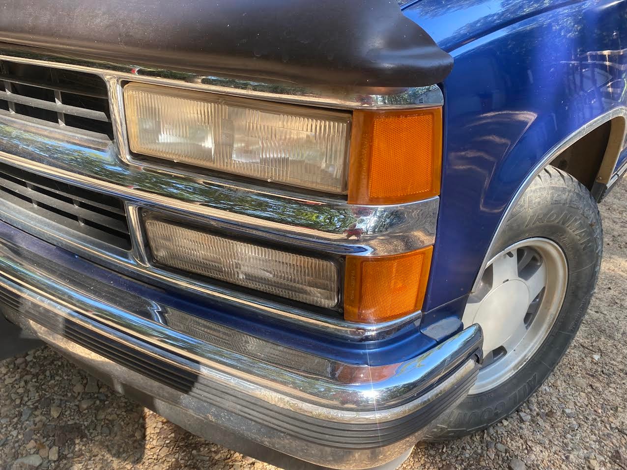 Clear, restored passenger side headlights on blue Chevy C/K truck after restoration