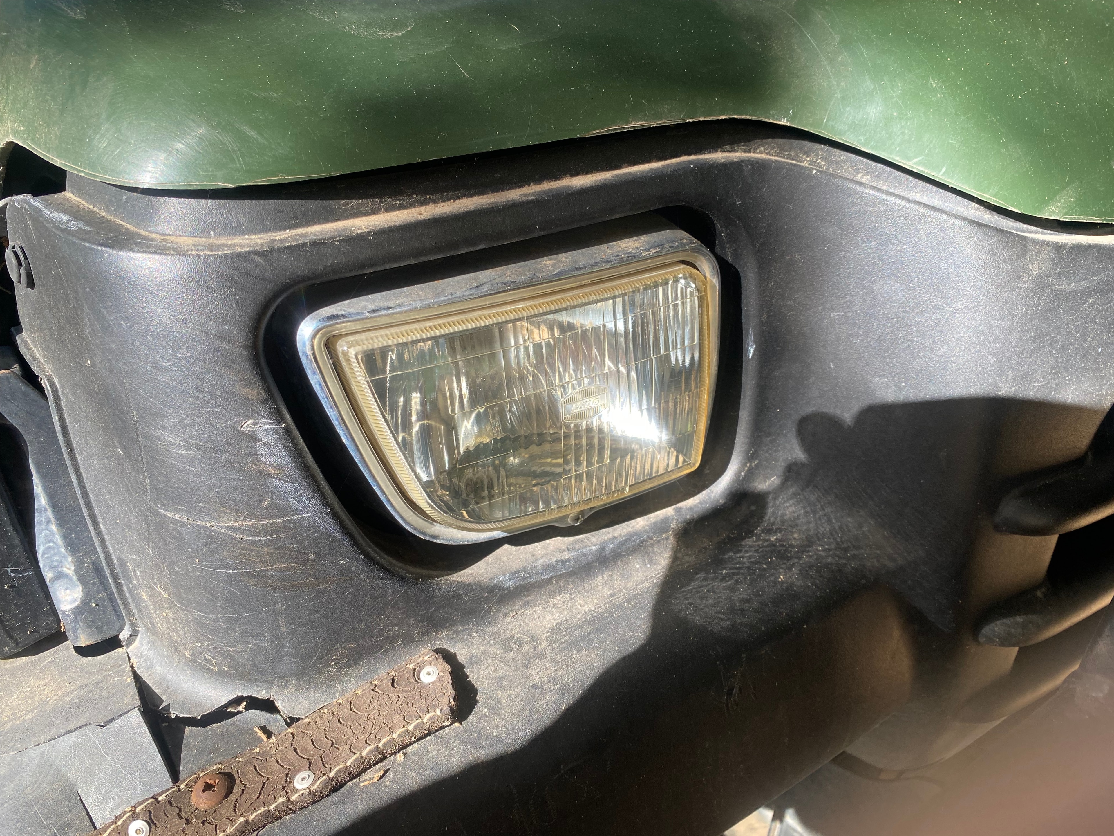 Clear, restored rectangular headlight on green John Deere utility vehicle after restoration